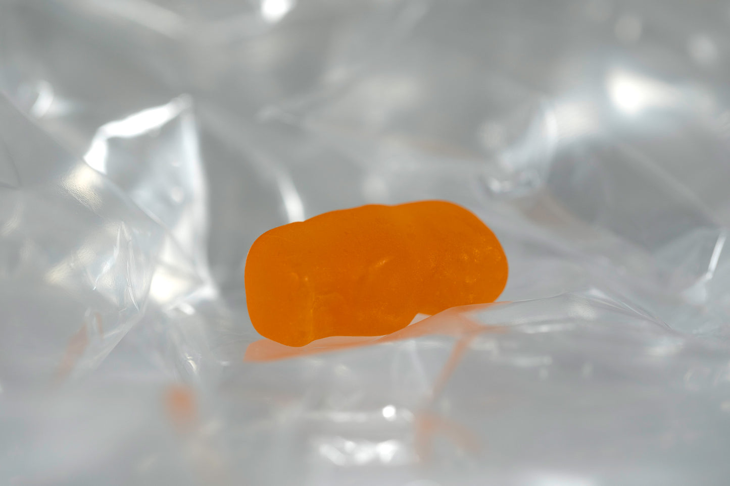 Orange translucent baby-shaped figure resting horizontally within softly illuminated transparent material.