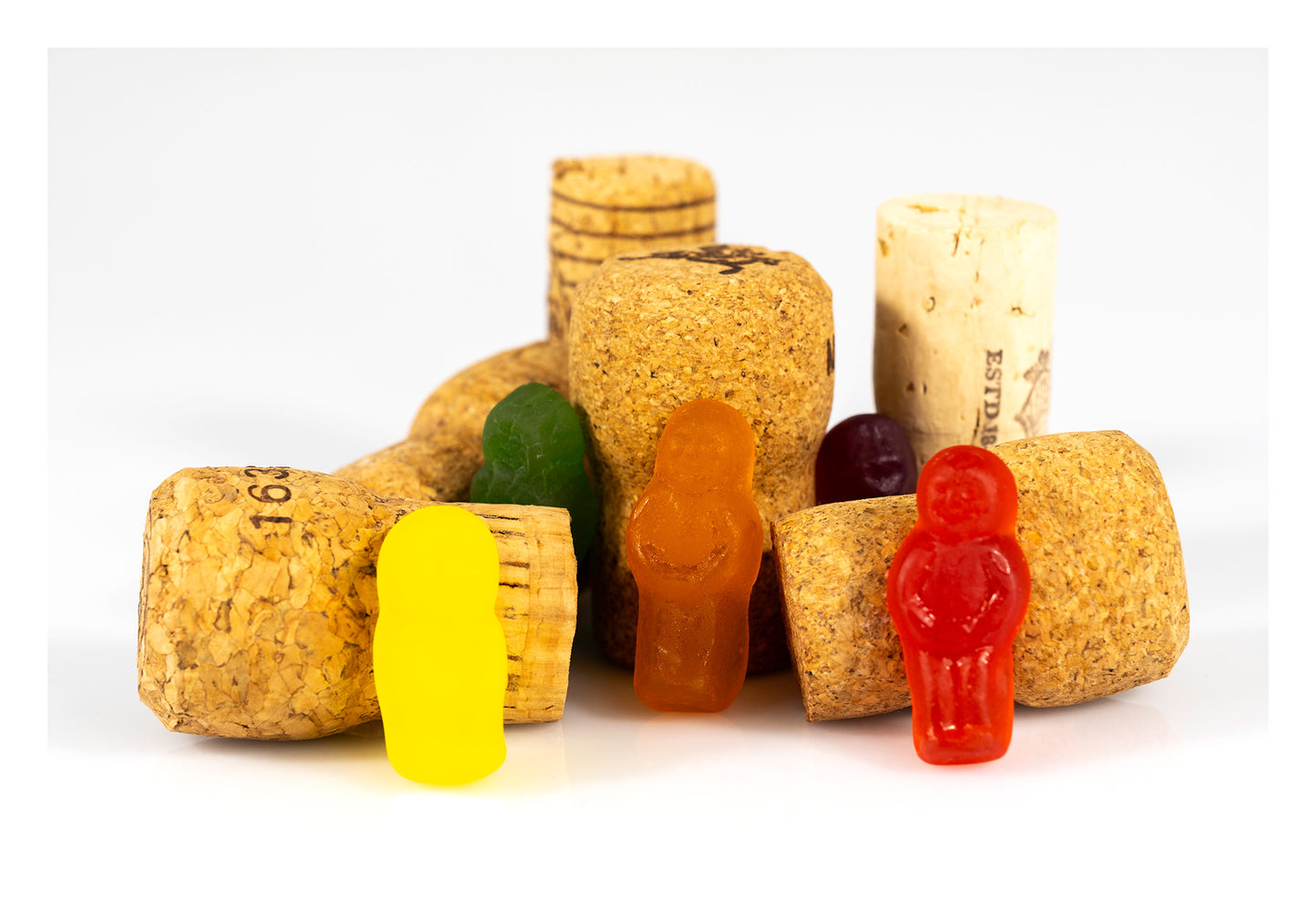 Colourful confectionery figures arranged among a collection of textured wine corks on a white background in What A Corker - 266641v1.