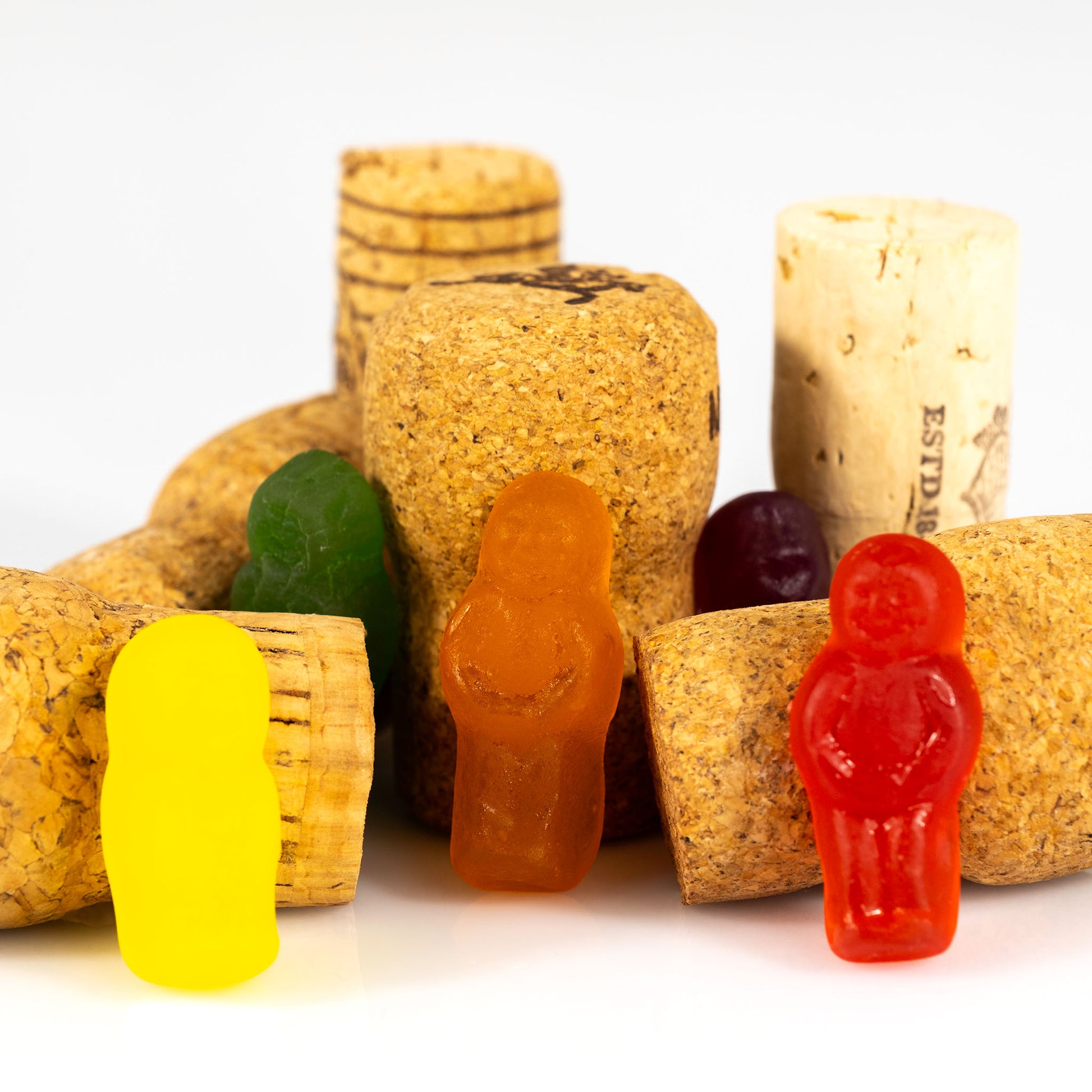 Close view of yellow, orange and red confectionery figures standing among oversized wine corks in What A Corker - 266641v1.