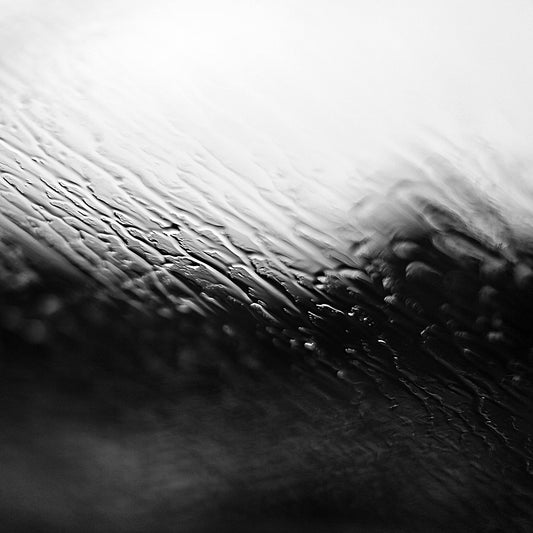 Coastal Noir 7952 - Close Detail View, monochrome photograph with rippling water and rain-speckled glass creating soft abstract coastal textures.