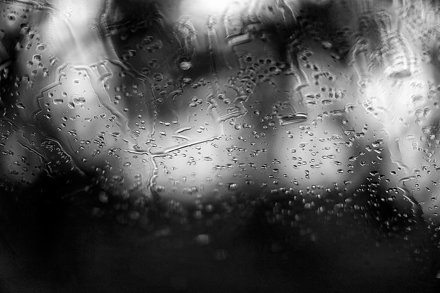 Coastal-Noir 8147 - 90x60cm, black and white coastal photograph with rain-speckled glass creating soft abstract textures over blurred landscape.