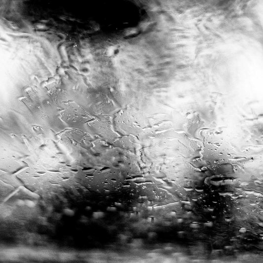 Coastal Noir 7185 - Close Detail View, Black and white abstract coastal photograph with people with umbrellas blurred behind rain-speckled glass, minimalist fine art print.