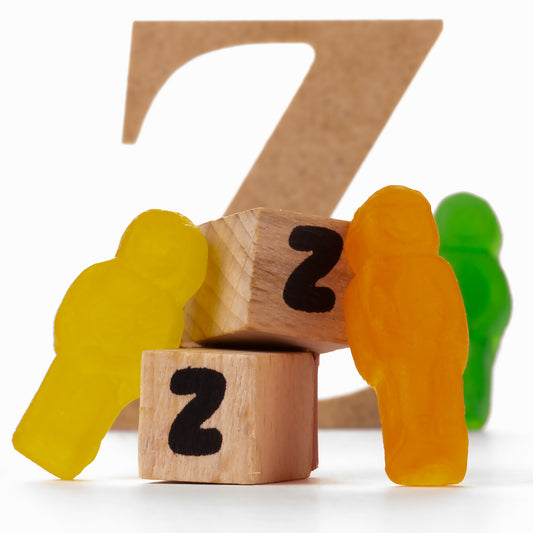 Catching Some ZZZ's 1493v3 - Close Detail View, playful fine art photograph featuring multicoloured jelly figures resting against wooden blocks marked with the letter Z, backed by large cardboard Zs, limited edition by Raymond Mather, ART1.