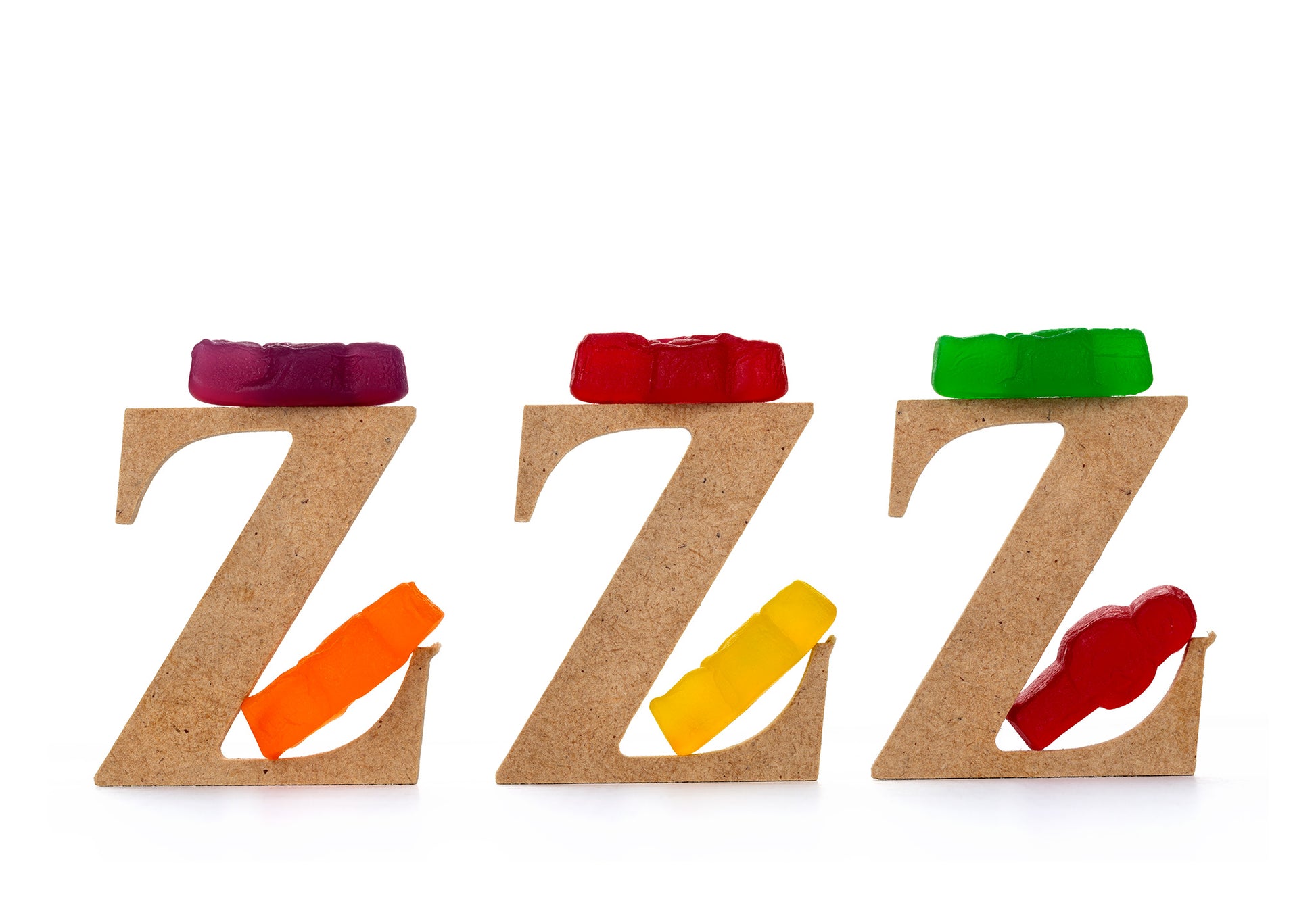 Catching Some ZZZ’s 1501 - 104x74cm, playful fine art photograph featuring three wooden letter Zs each topped with gummy bears and supported by colourful jelly baby figures, part of the Cliché Life series by Raymond Mather, ART1.