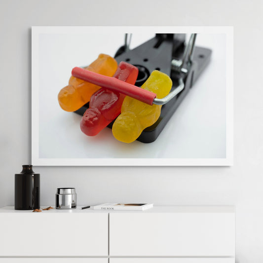 Caught in a Trap 3027 - Room View, fine art photograph of three gummy jelly figures caught beneath the bar of a black metal trap, captured with precision and pop-art wit by Raymond Mather, ART1.