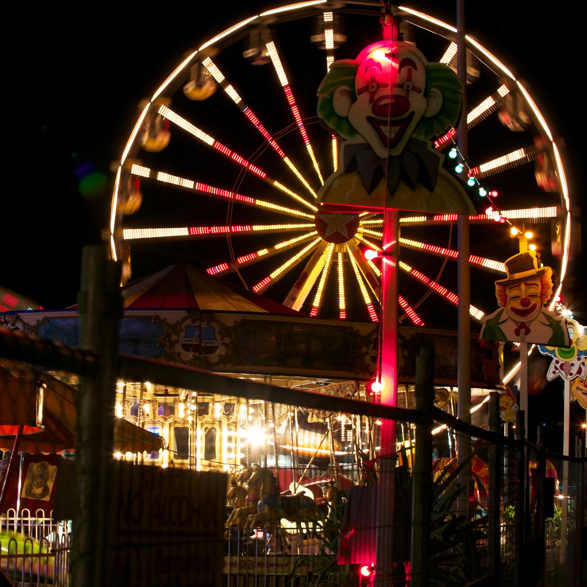 Fairground Carnival Lights 6900083 - Close Detail View, night carnival view with Ferris wheel, glowing rides, and striking clown figure, fine art limited edition print by Raymond Mather, ART1.