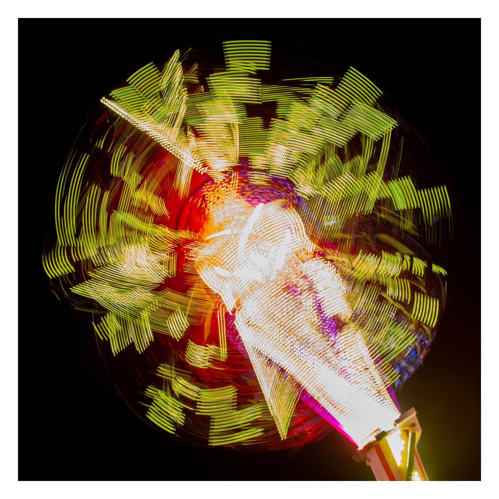 Fairground Carnival Lights 6900132 - 104x104cm, a long exposure photograph of a spinning carnival ride, captured in a dazzling explosion of yellow, red, and white lights radiating from a central axis against a deep black sky. The blurred movement forms abstract, circular patterns, creating a vibrant and kinetic visual effect.