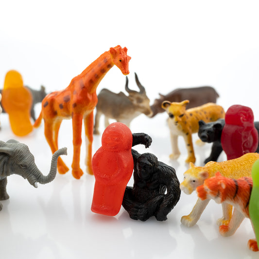 Life’s a Zoo 2816v1 - Close Detail View, whimsical fine art photograph featuring colourful gummy figures surrounded by miniature toy animals including a giraffe, elephant, lion, zebra and chimpanzee on a white reflective surface, playfully evoking the chaos and charm of life as a zoo, limited edition by Raymond Mather, ART1.
