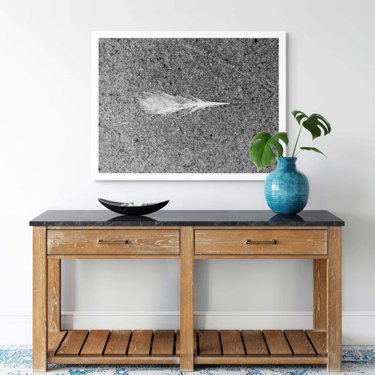 Monochrome Mix - Beach - Feather - 184019 - Room View, A single white feather lying on textured sand, captured in black and white with sharp detail and high contrast. Limited edition fine art print.