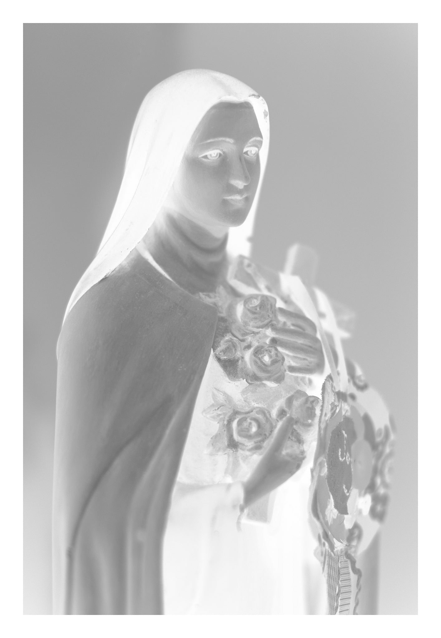 Monochrome Mix - Icons on the Mantel - 183073 - 74x104cm, A soft black and white image of Saint Thérèse of Lisieux holding roses and a cross, exuding peaceful grace and spiritual tenderness.