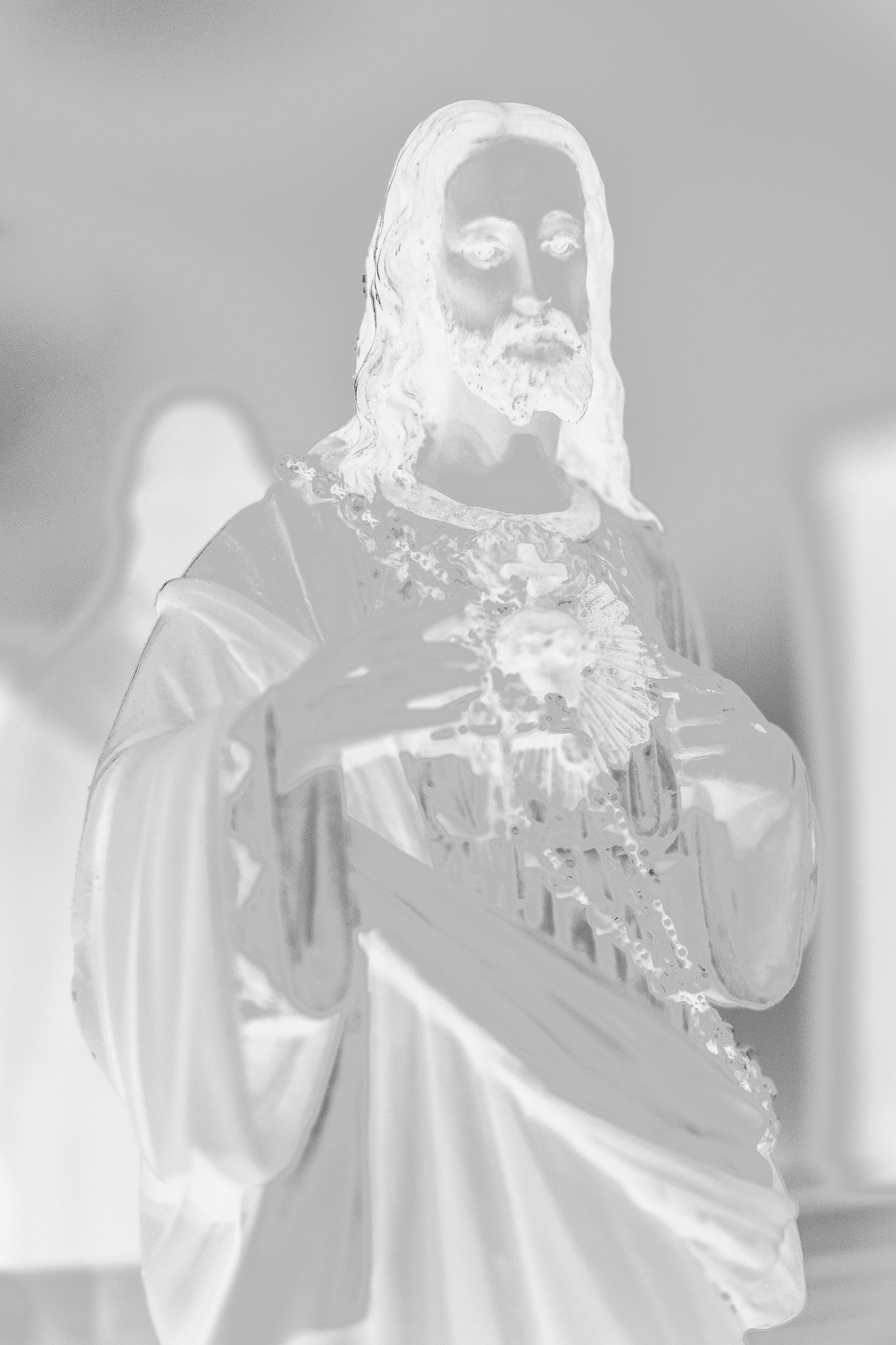 Monochrome Mix - Icons on the Mantel - 183081 - 60x90cm, Soft-focus black and white image of a Sacred Heart of Jesus statue, with subtle ethereal lighting evoking spiritual presence and quiet reverence.
