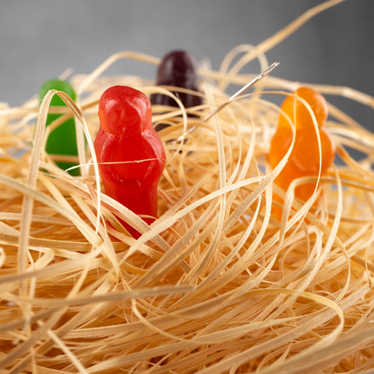 Needle in a Haystack 2523v1 - Close Detail View, conceptual fine art photograph by Raymond Mather featuring colourful jelly baby figures nestled in straw with a real sewing needle subtly placed, playfully reimagining the classic idiom in vibrant pop art style.