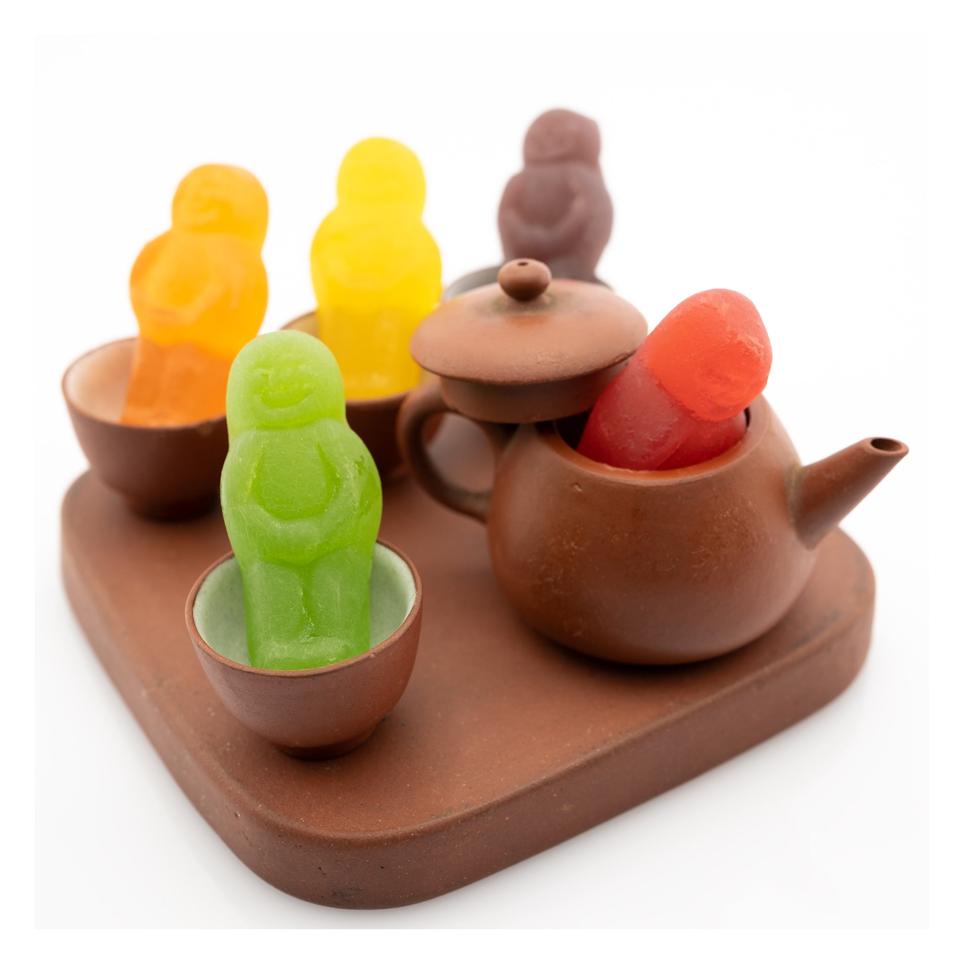 Not My Cup of Tea 3013v2 - 104x104cm, conceptual fine art photograph by Raymond Mather featuring brightly coloured jelly baby figures arranged within a miniature clay tea set, playfully subverting the familiar idiom in a scene of joyful visual whimsy.
