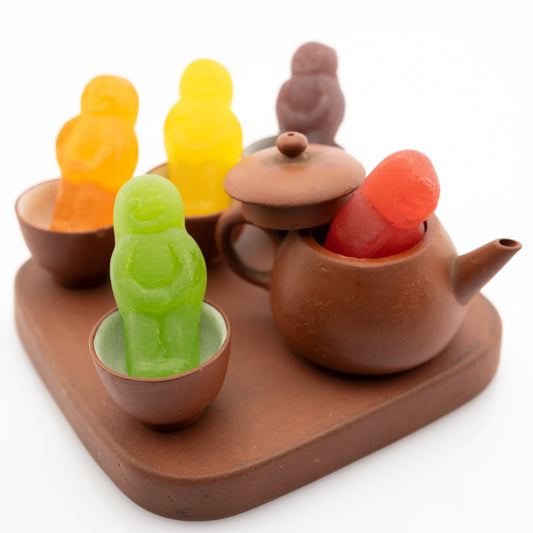 Not My Cup of Tea 3013v2 - Close Detail View, conceptual fine art photograph by Raymond Mather featuring brightly coloured jelly baby figures arranged within a miniature clay tea set, playfully subverting the familiar idiom in a scene of joyful visual whimsy.