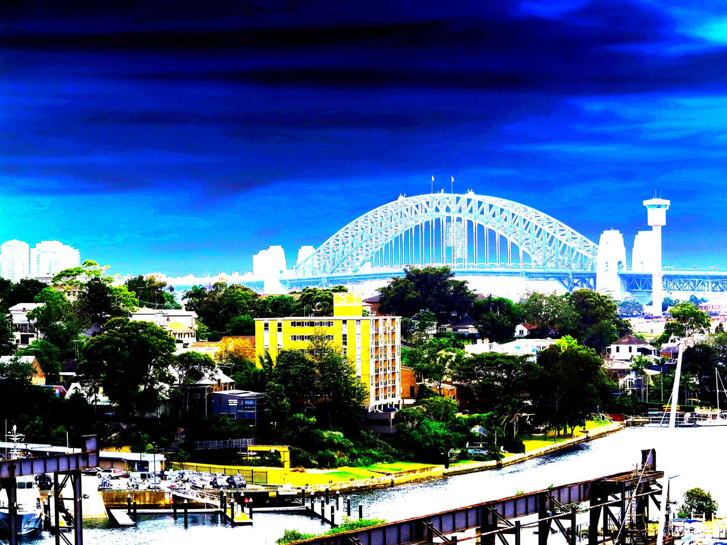POPscape Sydney - Harbour Bridge View - 190022v89 - 90x67.5cm, Vibrant stylised view of Sydney Harbour Bridge with saturated blue sky, suburban rooftops, and a bold yellow building in the foreground overlooking the water.