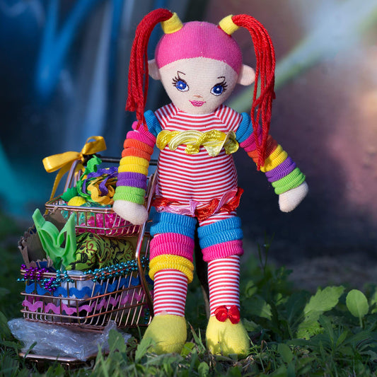 Trolley Dolly - Series No.1: 197291 - Close Detail View, a colourful handmade cloth doll with red pigtails stands beside a mini trolley filled with ribbons, trinkets, and found objects. Her shadow is cast onto a galaxy style mural wall in the background. The image explores homelessness, identity, and play through symbolic layering.