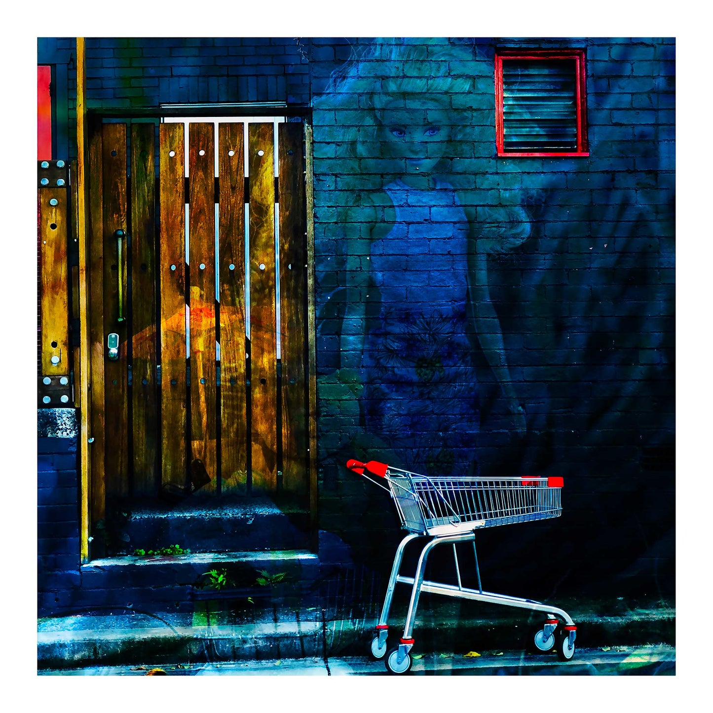 Trolley Dolly - Series No.2: 19E2255v12 - 74x74cm, a translucent doll like woman with blonde hair is layered against a dark blue brick wall. A red handled shopping trolley sits at the curb, and a wooden slatted door glows with hints of fruit and market textures. The scene symbolises homelessness, invisibility, and social neglect.