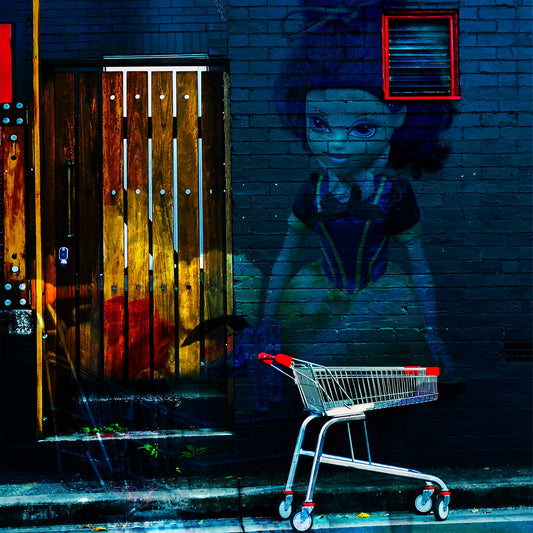 Trolley Dolly - Series No.3: 19E2255v2 - Close Detail View, a fine art photograph featuring a stylised mural of a girl resembling Snow White painted on a dark brick wall next to a wooden door, with a red and silver shopping trolley in the foreground. The artwork contrasts innocence with urban decay.