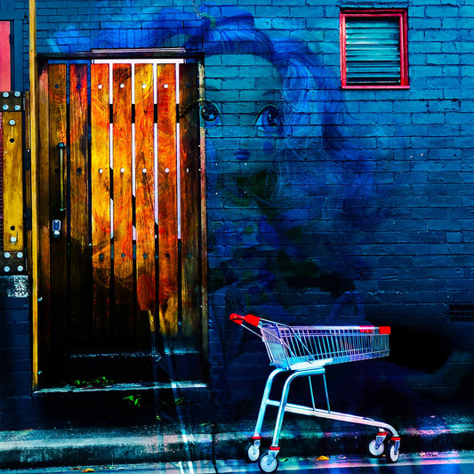 Trolley Dolly - Series No.2: 19E2255v7 - Close Detail View, a ghostly doll with large eyes emerges from a dark blue brick wall beside a red handled shopping trolley. A timber door glows with fiery textures layered from market imagery. The surreal scene explores invisibility, homelessness, and emotional fragility through layered urban symbolism.
