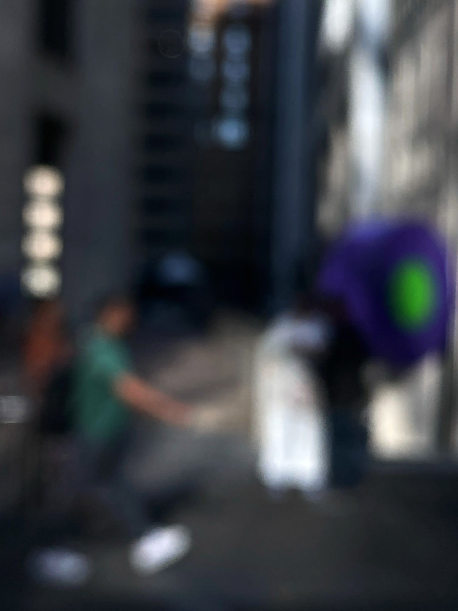 Urban Commute - Series No.1: 0960v1 - 67.5x90cm, a soft-focus image of a city commuter mid-stride beside a vivid purple umbrella, set between tall buildings in gentle light. An abstracted urban moment captured in motion. Limited edition fine art print by Raymond Mather.