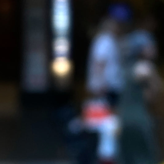Urban Commute - Series No.1: 0974v1 - Close Detail View, a soft-focus photograph of two blurred adult figures with a small child in red and white, framed by glowing city lights and vertical signage. A quiet moment of connection and motion captured in painterly abstraction. Limited edition fine art print by Raymond Mather.