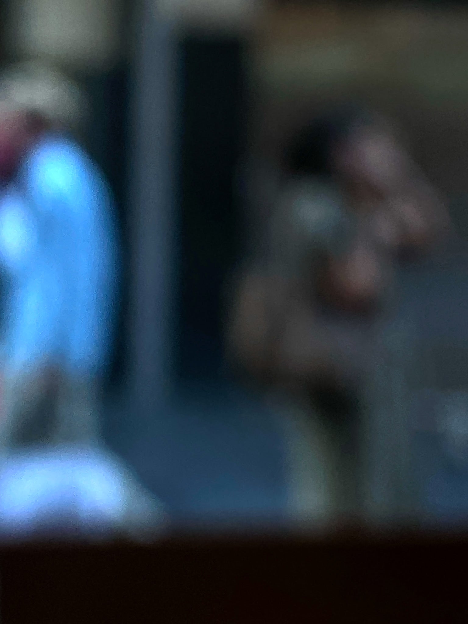 Urban Commute - Series No.1: 0978v1 - 67.5x90cm, a soft focus photograph of two city commuters: one in a blue shirt walking left, and another mid call, set against a shadowed urban backdrop. A contemplative image of separation and movement. Limited edition fine art print by Raymond Mather.