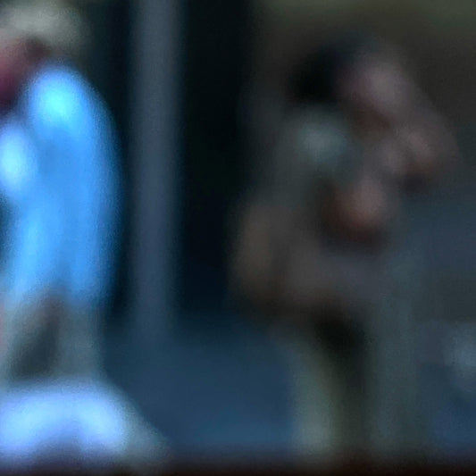 Urban Commute - Series No.1: 0978v1 - Close Detail View, a soft focus photograph of two city commuters: one in a blue shirt walking left, and another mid call, set against a shadowed urban backdrop. A contemplative image of separation and movement. Limited edition fine art print by Raymond Mather.