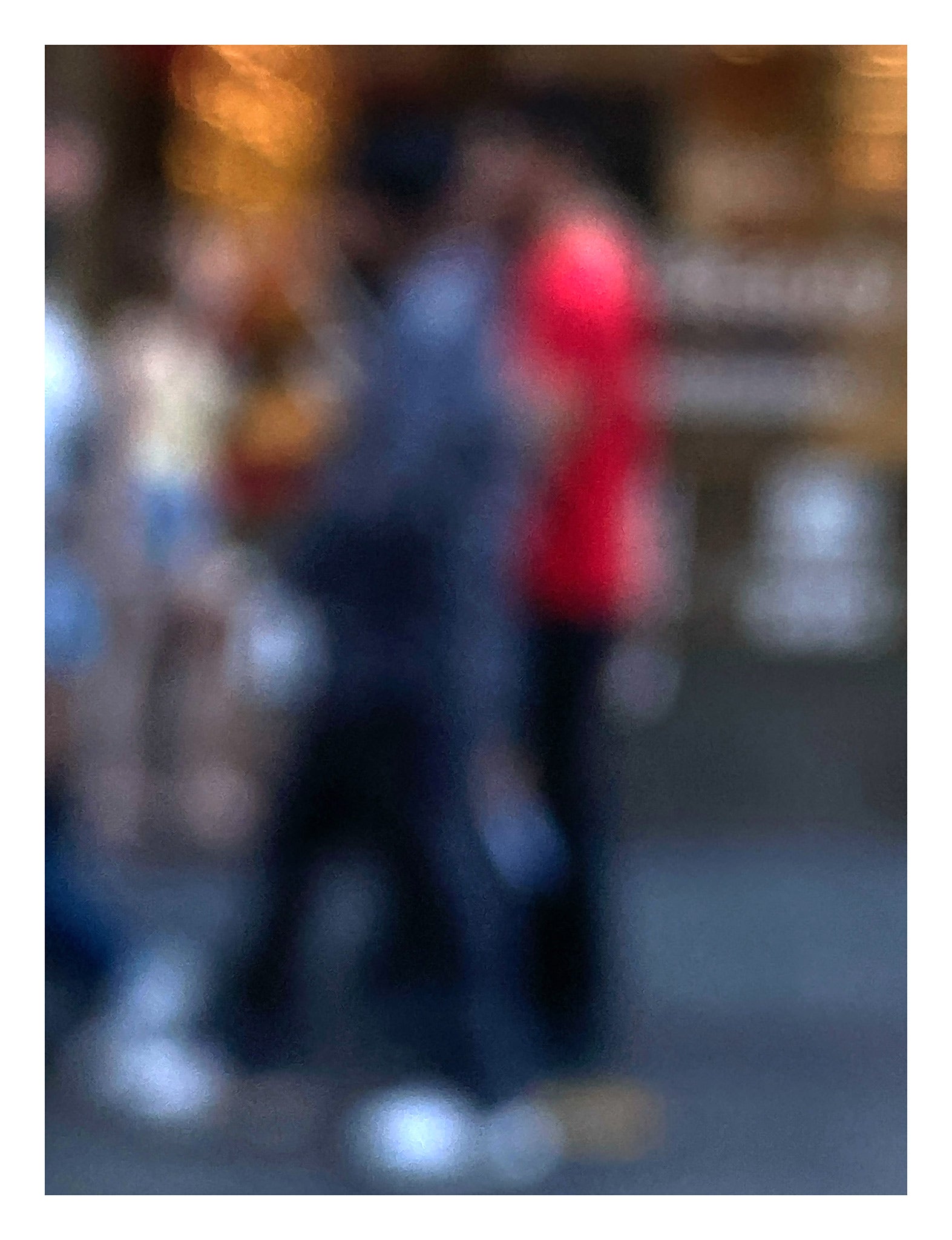 Urban Commute - Series No.1: 0983v1 - 81.5x104cm, a soft focus photograph of blurred pedestrians in motion, with one figure in bright red passing a golden-lit city storefront. A painterly exploration of rhythm, anonymity, and colour in the urban commute. Limited edition fine art print by Raymond Mather.