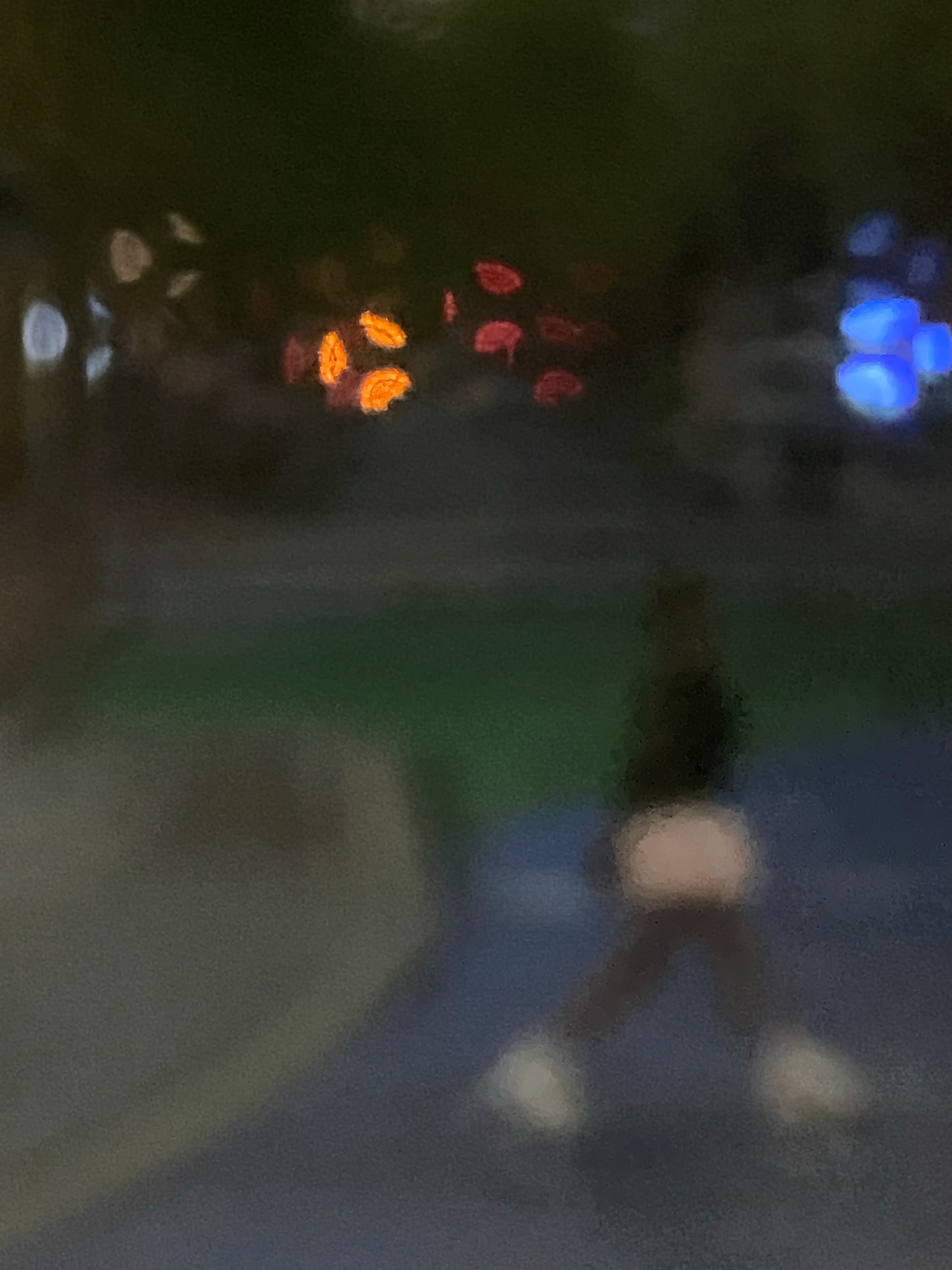 Urban Commute - Series No.1: 1206v1 - 67.5x90cm, a soft focus evening image of a single blurred commuter walking across a dim city path, with scattered lights in red, orange, and blue glowing in the distance. A moody, atmospheric urban scene in motion. Limited edition fine art print by Raymond Mather.