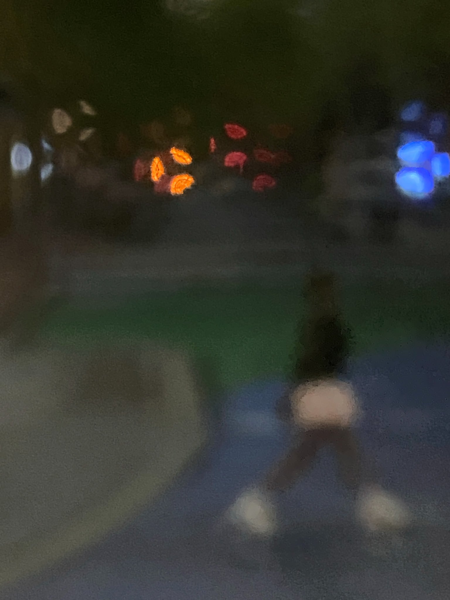 Urban Commute - Series No.1: 1206v1 - 67.5x90cm, a soft focus evening image of a single blurred commuter walking across a dim city path, with scattered lights in red, orange, and blue glowing in the distance. A moody, atmospheric urban scene in motion. Limited edition fine art print by Raymond Mather.