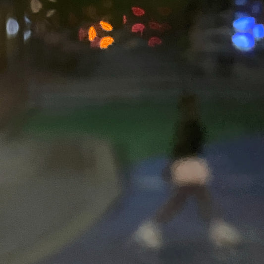 Urban Commute - Series No.1: 1206v1 - Close Detail View, a soft focus evening image of a single blurred commuter walking across a dim city path, with scattered lights in red, orange, and blue glowing in the distance. A moody, atmospheric urban scene in motion. Limited edition fine art print by Raymond Mather.