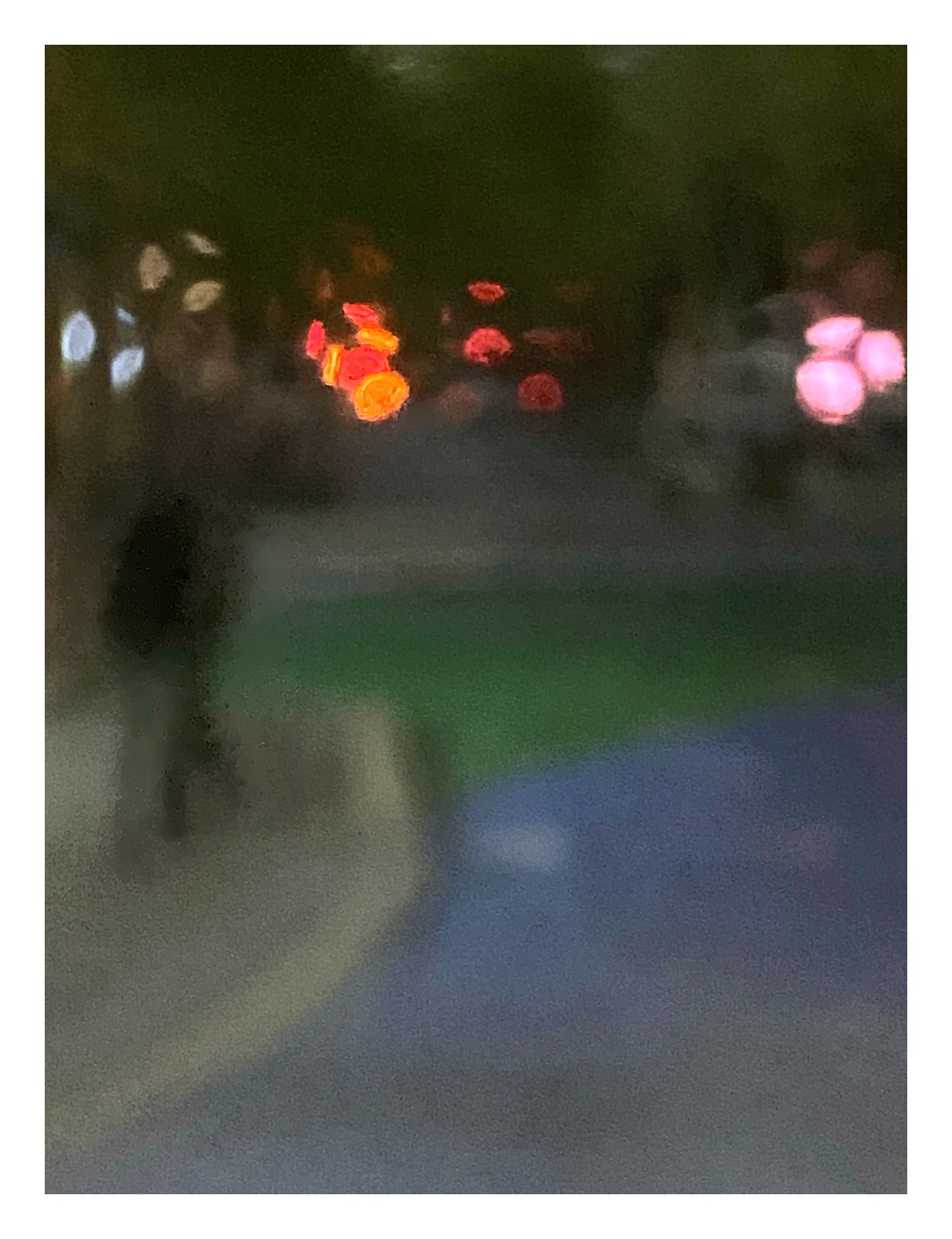 Urban Commute - Series No.1: 1209v1 - 81.5x104cm, a soft focus night scene featuring a solitary walker in a darkened streetscape. Vibrant bokeh lights in red, amber, and pink hover in the distance, surrounded by deep shadow and soft city tones. Limited edition fine art print by Raymond Mather