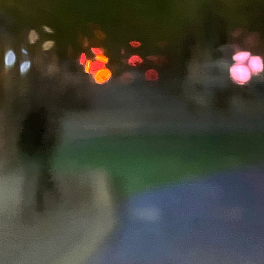 Urban Commute - Series No.1: 1209v1 - Close Detail View, a soft focus night scene featuring a solitary walker in a darkened streetscape. Vibrant bokeh lights in red, amber, and pink hover in the distance, surrounded by deep shadow and soft city tones. Limited edition fine art print by Raymond Mather.