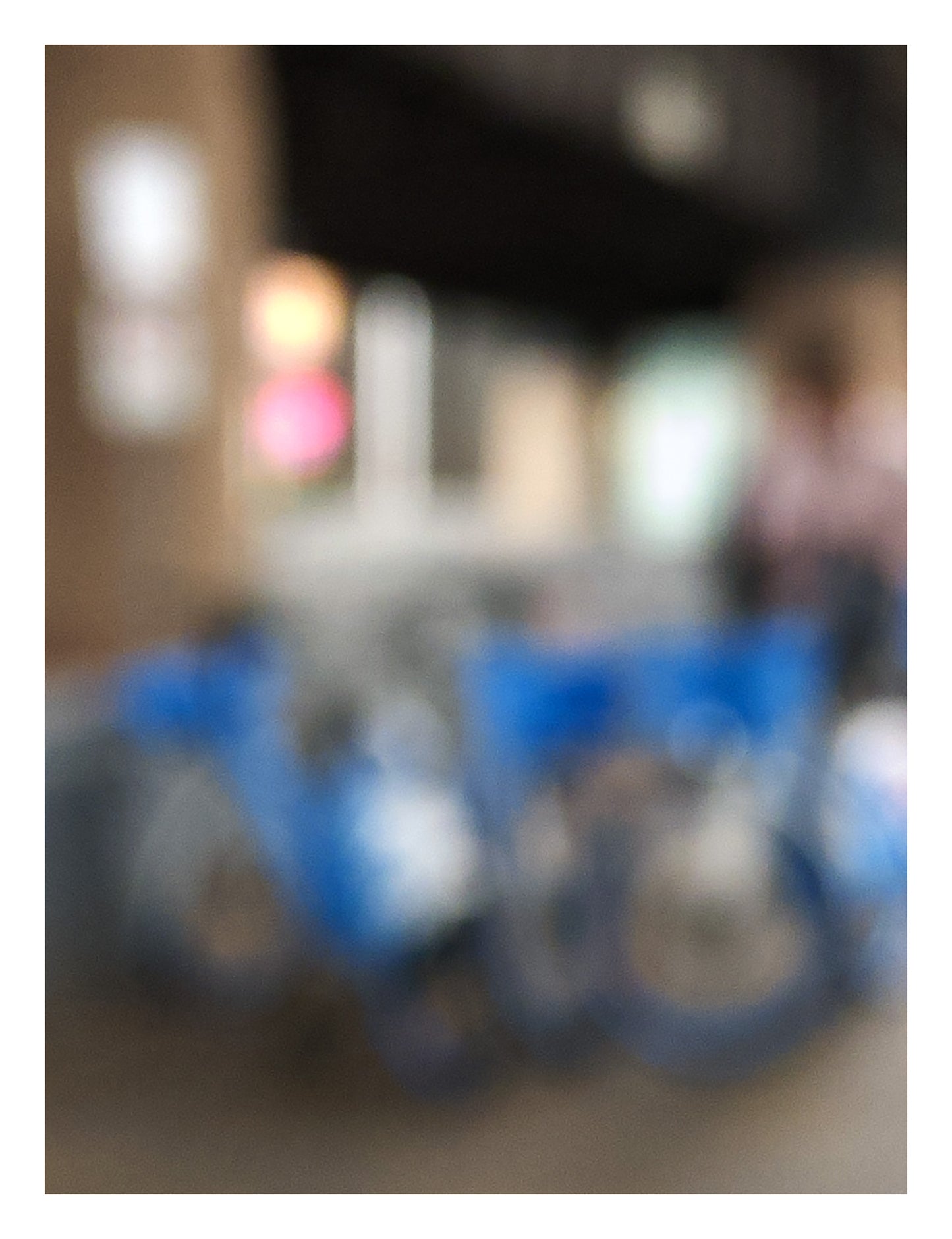 Urban Commute - Series No.1: 9646v1 - 81.5x104cm, a soft focus image of a group of blue city e-bikes parked in a cluster, with blurred lights and architecture in the background. A passing figure adds motion to the scene. Limited edition fine art print by Raymond Mather.