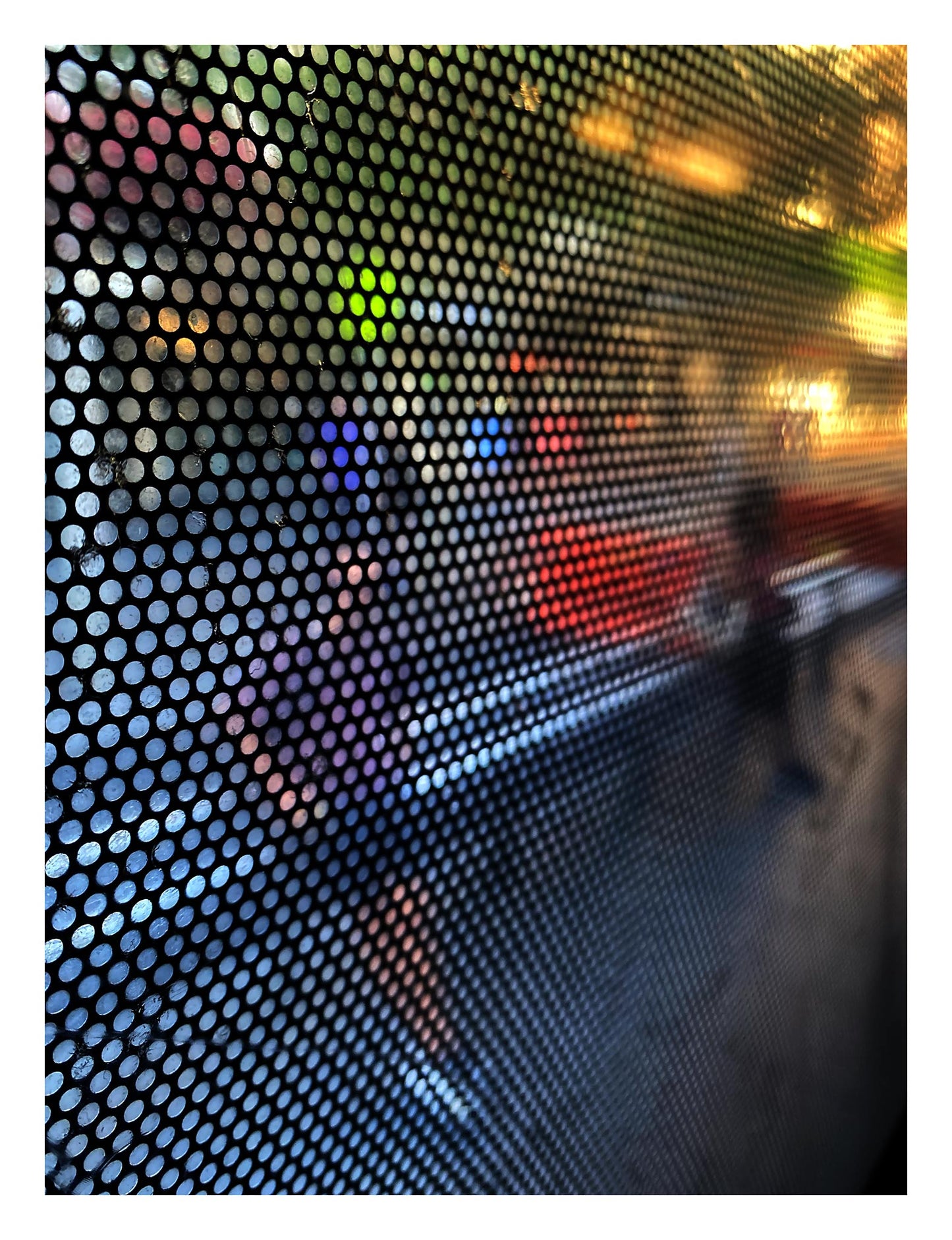 Urban Commute - Series No.2: 0785 - 81.5x104cm, fine art photograph by Raymond Mather featuring a blurred pedestrian viewed through a perforated window screen. Vibrant colours of red, purple, and green shimmer across the gridded surface, creating a dynamic abstract portrait of city life in motion.