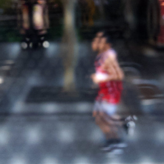 Urban Commute - Series No.2: 9199v1 - Close Detail View, fine art photograph by Raymond Mather featuring a blurred runner in red, captured mid-stride through a soft patterned lens. The urban backdrop is abstracted into colour and shadow, evoking a dreamlike sense of motion and energy. 