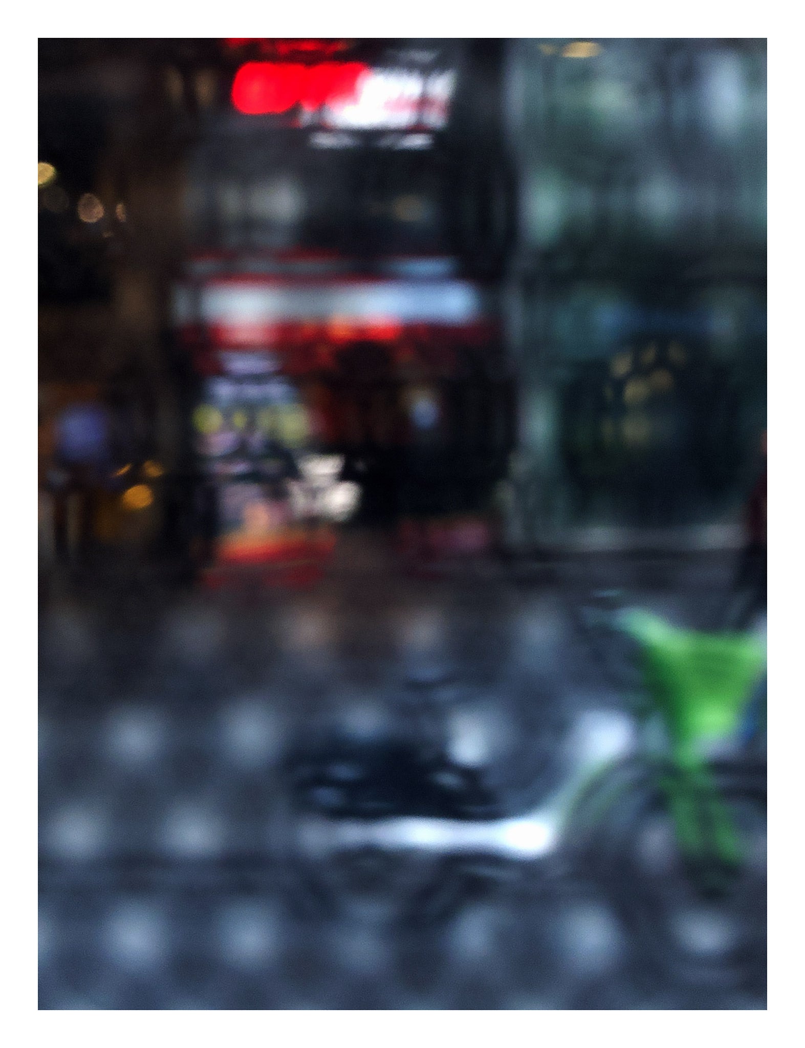Urban Commute - Series No.2: 9206v1 - 81.5x104cm, fine art photograph by Raymond Mather featuring a blurred green bike in the foreground, with a red neon-lit storefront behind a softly distorted surface. A moody and abstract urban scene evoking energy and reflection.