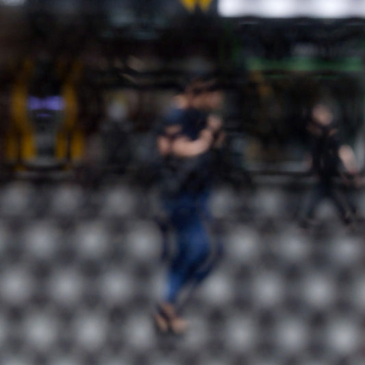 Urban Commute - Series No.2: 9609 - Close Detail View, fine art photograph by Raymond Mather featuring a blurred morning commuter with a backpack, seen mid-stride through a patterned surface. Another figure passes in the background. A layered urban image of movement and solitude.