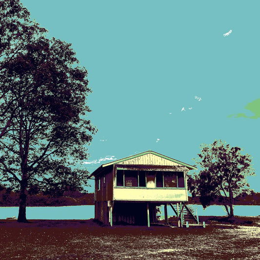 Vivid Country - Urunga River House - 6393v44 - Close Detail View, a raised riverfront house stands beside tall silhouetted trees in Urunga, rendered in muted Pop Art tones of teal, brown, and green. A tranquil riverscape with a picnic bench evokes a sense of stillness and simplicity.